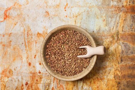 Lentils in a wooden bowl and on a rusty metal background in a top viewの写真素材