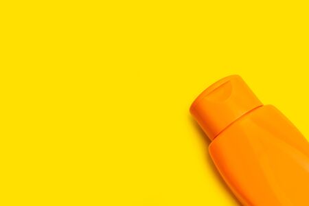 An orange suntan cream bottle on an orange backgroundの写真素材