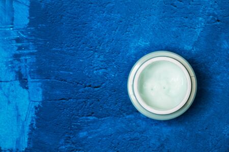 Moisturizer cream bottle on a textured classic blue background in a top viewの写真素材
