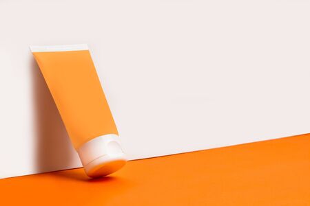 Moisturizer cream soft tube on a white and orange background