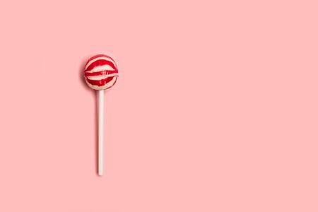 A red and white lollipop on a pink backgroundの写真素材