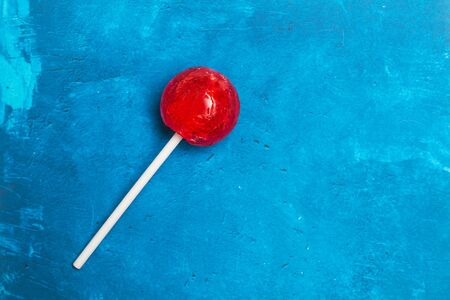 Red lollipop on a textured classic blue backgroundの写真素材