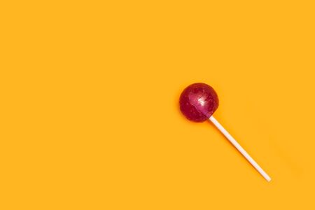 Purple lollipop on a yellow background in a top viewの写真素材