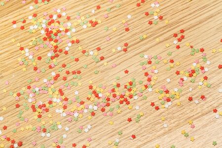 Colored star dragees on a wooden table in a top viewの写真素材