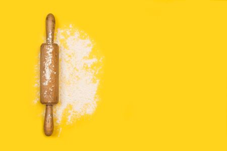 Rolling pin with flour on a yellow background in a top viewの写真素材