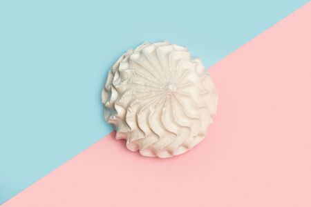 Meringue on a pink and light blue background in a top view