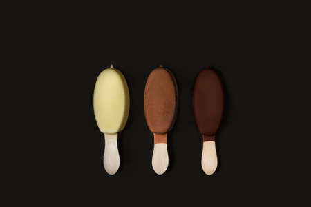 Chocolate dipped ice lolly on a brown and yellow backgroundの写真素材