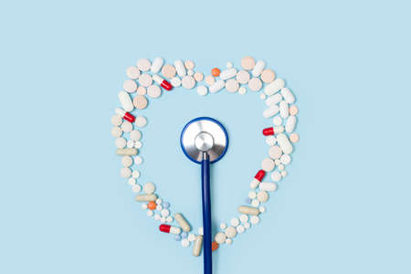A stethoscope and a heart made with medical pills on a light blue backgroundの写真素材