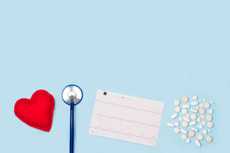 A stethoscope, an electrocardiogram and medical pills on a light blue backgroundの写真素材