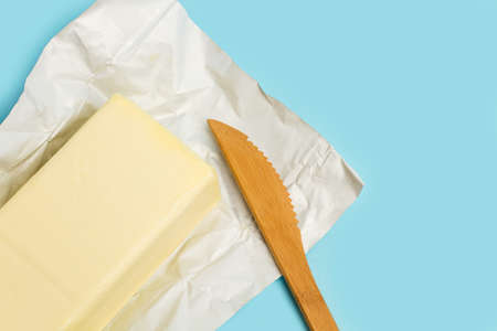 A block of butter on a aluminum paper on a light blue backgroundの写真素材