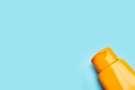 An plastic orange suntan lotion bottle on a light blue background with copy spaceの写真素材