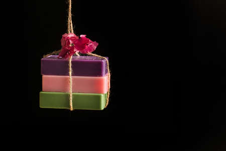 Colored soap bars hanging on a dark background with copy space