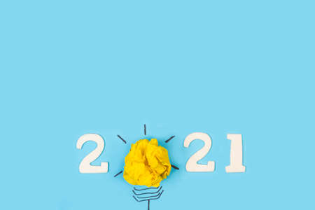 2021 year greeting with a light bulb made with paper on a blue backgroundの写真素材