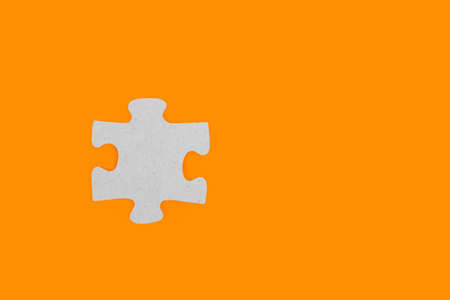 A puzzle piece on an orange background in a close up viewの写真素材