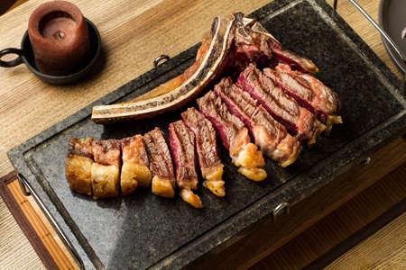 Sliced grilled steak with bone on a cooking stone in a top viewの写真素材
