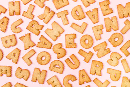 Assorted alphabet letters cookies on a pink background background