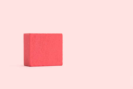 A pink wooden block on a pink background with copy space
