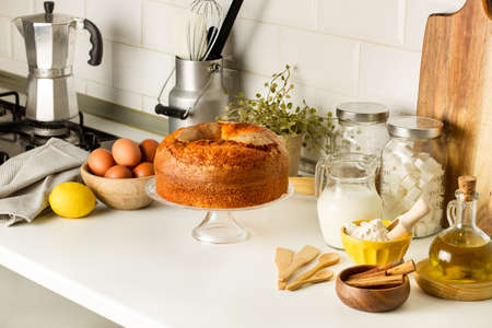 A vanilla cake and ingredients on a cake stand on the kitchen countertop