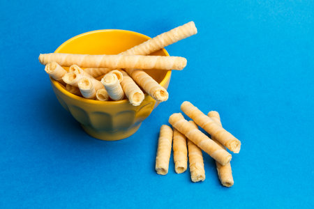 Wafer rolls in a yellow bowl and on a blue background