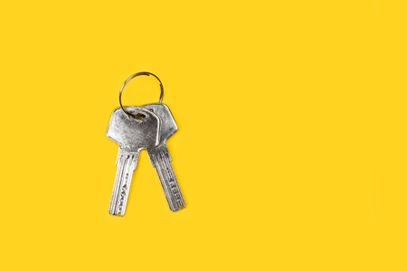 Metal secure keys on yellow background with copy spaceの写真素材