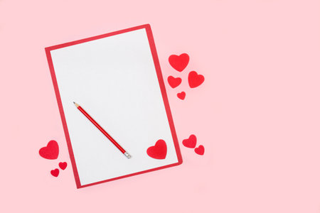 A valentine's greeting card with copy space and red paper hearts on a pink backgroundの写真素材