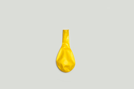 A deflated yellow balloon on a gray background with copy spaceの写真素材