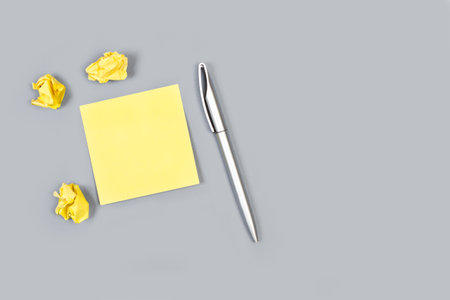 Blank sticky note and a gray pen on a gray background
