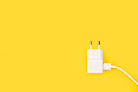 A smartphone charger with cable on a yellow backgroundの写真素材