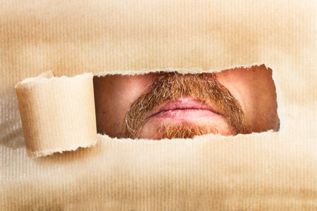 A man mouth through a hole of a tear brown paperの写真素材
