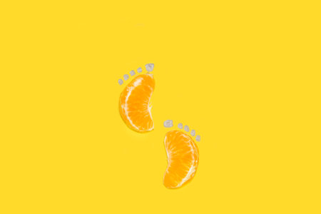 Footprints made with tangerine segments on a yellow backgroundの写真素材