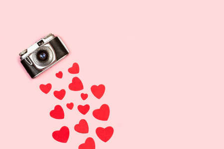 A vintage camera with red hearts on a pink backgroundの写真素材