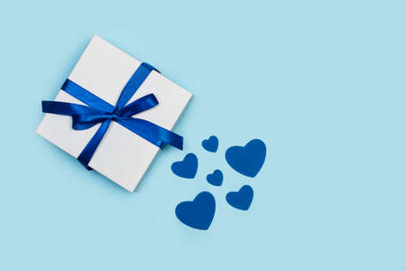 A gift with paper blue hearts on a light blue backgroundの写真素材