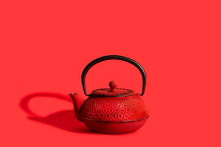 A red japanese teapot on a red backgroundの写真素材