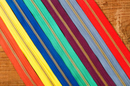 Colored zippers on a wooden table in a top viewの写真素材