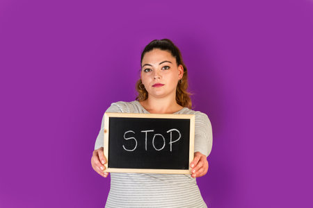 Curvy woman holding a small blackboard with stop word write in it