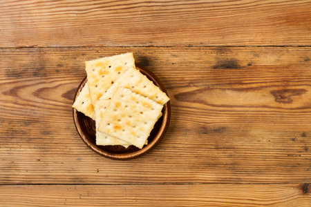 Cracker biscuits in a wooden bowl on a wooden table in a top viewの写真素材