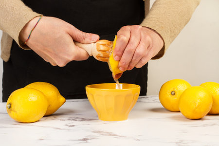 Woman squeezing a half lemon with a wooden squizzer