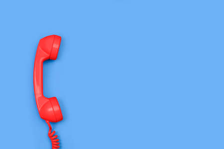 An old red telephone receiver on a blue background with copy spaceの写真素材
