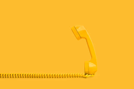 An vintage yellow telephone on a yellow background with copy space
