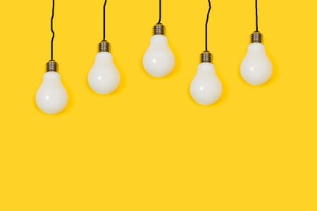 Lightbulbs hanging on a yellow background with copy space. Black lines like cables.