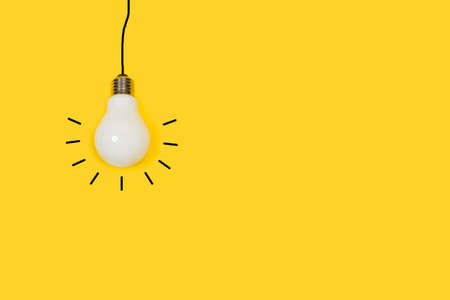 Lightbulb hanging on a yellow background with copy space. Black line like cable
