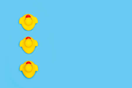 Three yellow rubber toy ducks on a blue background with copy space