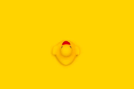 Yellow rubber toy duck on a yellow background in a top viewの写真素材