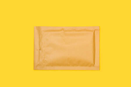 A brown padded envelope on a yellow backgroundの写真素材