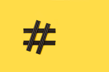 Hashtag sign made with black plastic straw on a yellow backgroundの写真素材