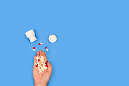 Woman hand holding medical pills on a blue background