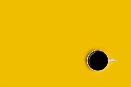 Cup of coffee on a yellow background in a top viewの写真素材