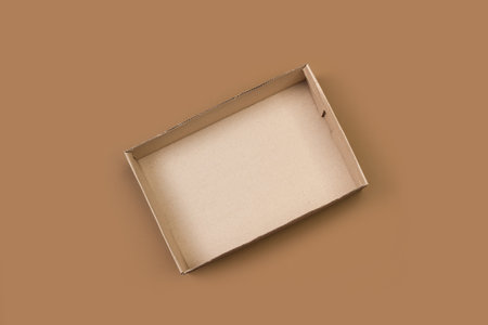 An open cardboard box in a top view on a brown background