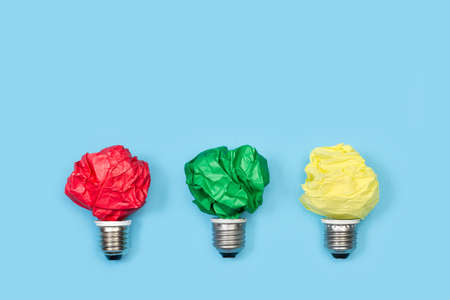 Light bulbs made with colored crumpled papers on a light blue backgroundの写真素材