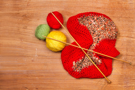Colored wool balls and wood knitting needles on a wooden background